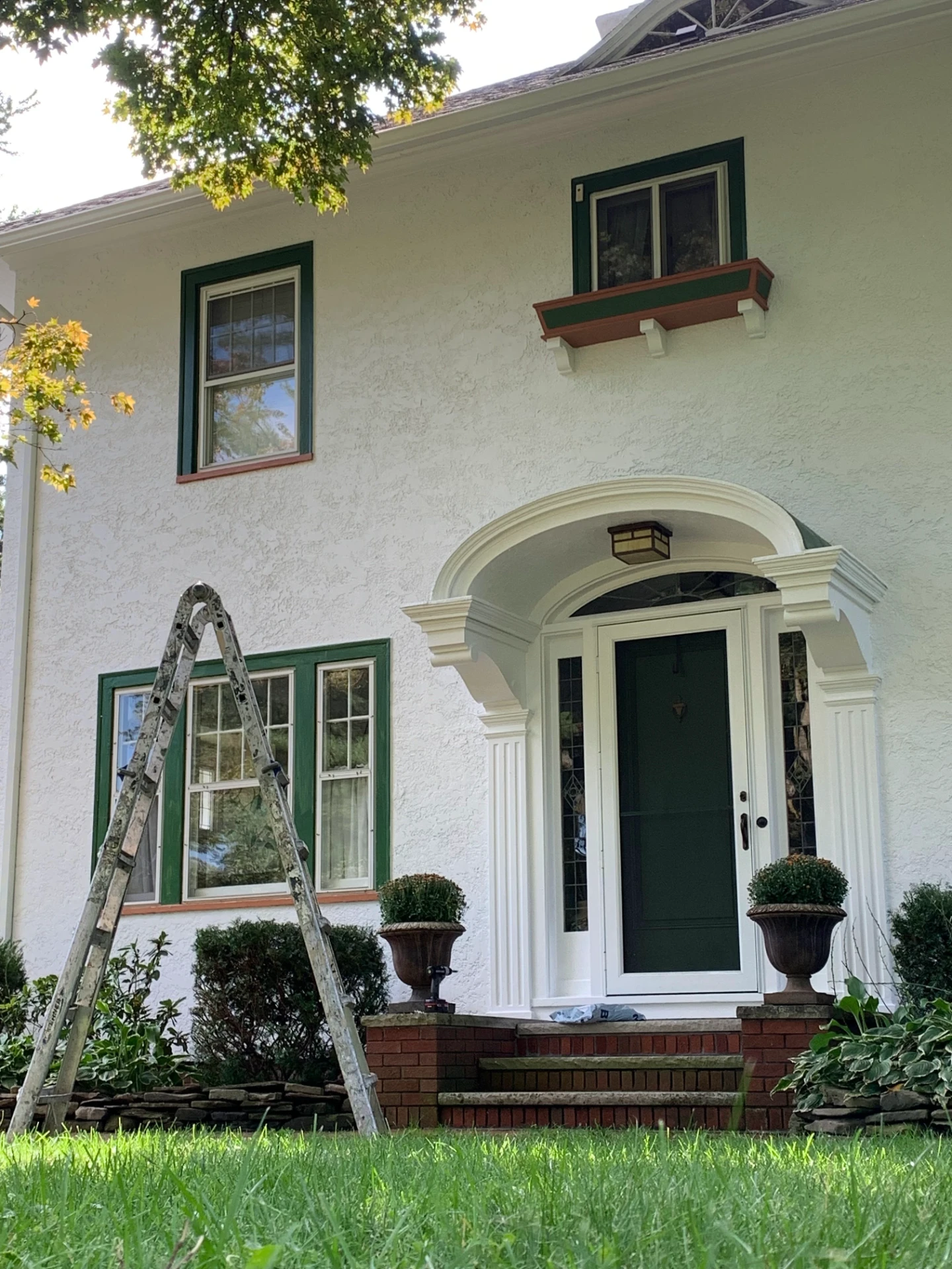 White stucco home with fresh dark green window trim painted by Constant Beaty Master Painter